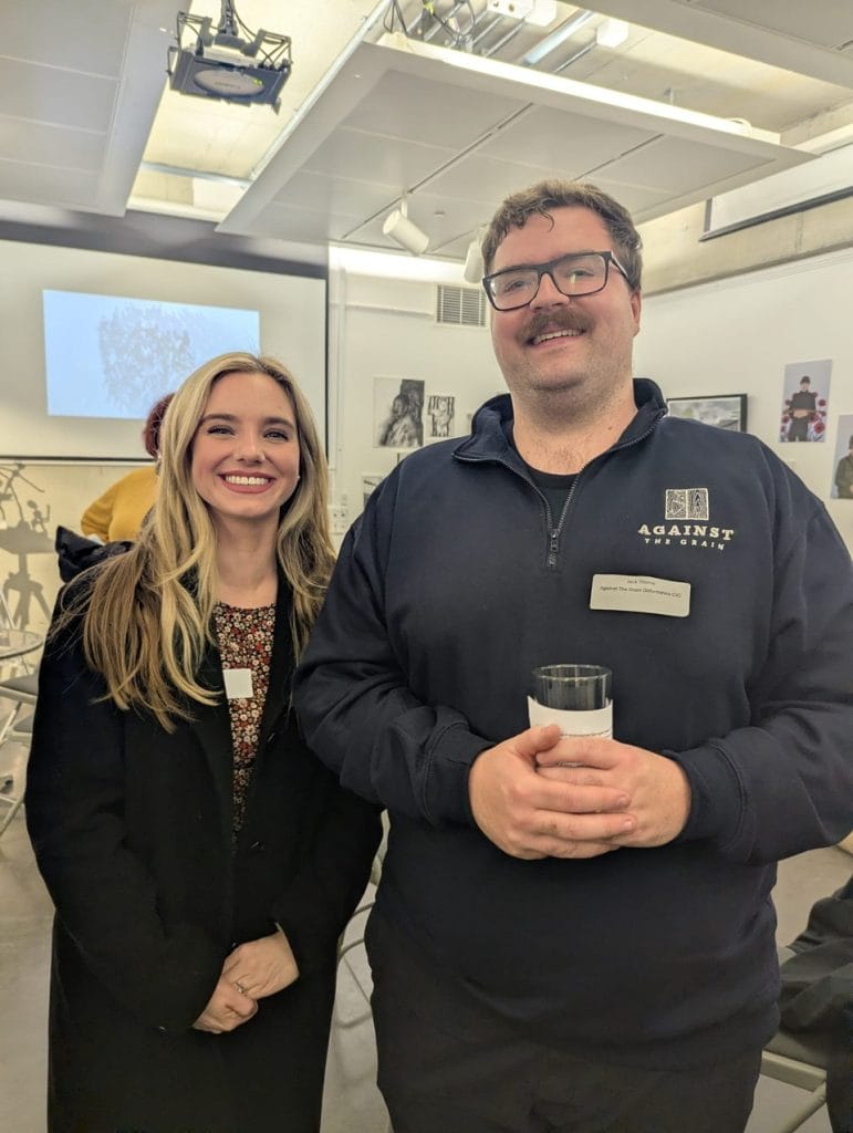 Smiling woman and man holding drinks at a gallery event
