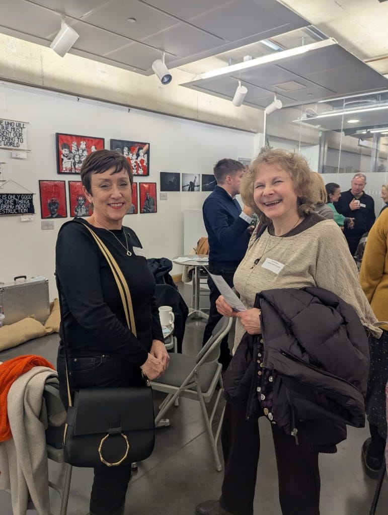 Two women chatting beside artwork at a gallery exhibition