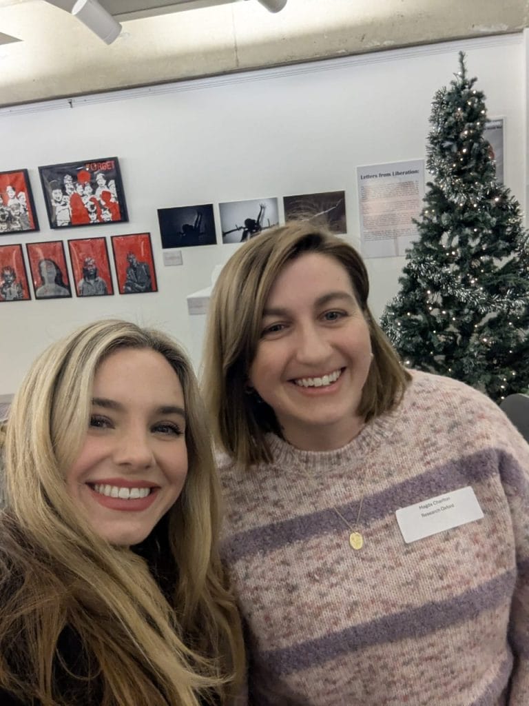 Two women smiling close together at a gallery networking event