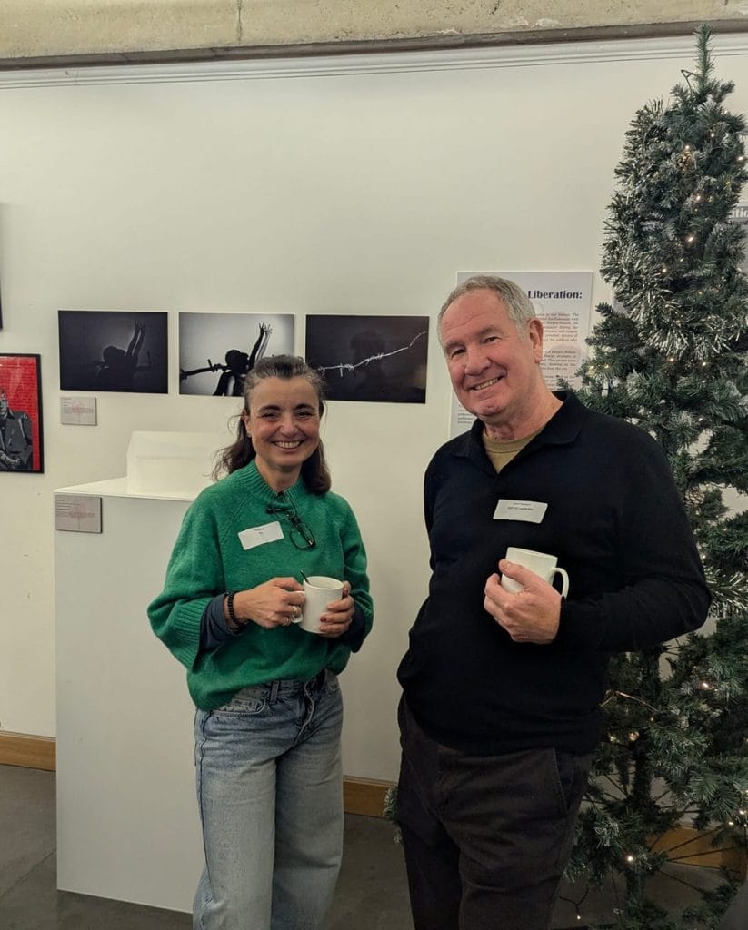 Two men chatting near a Christmas tree at a gallery event