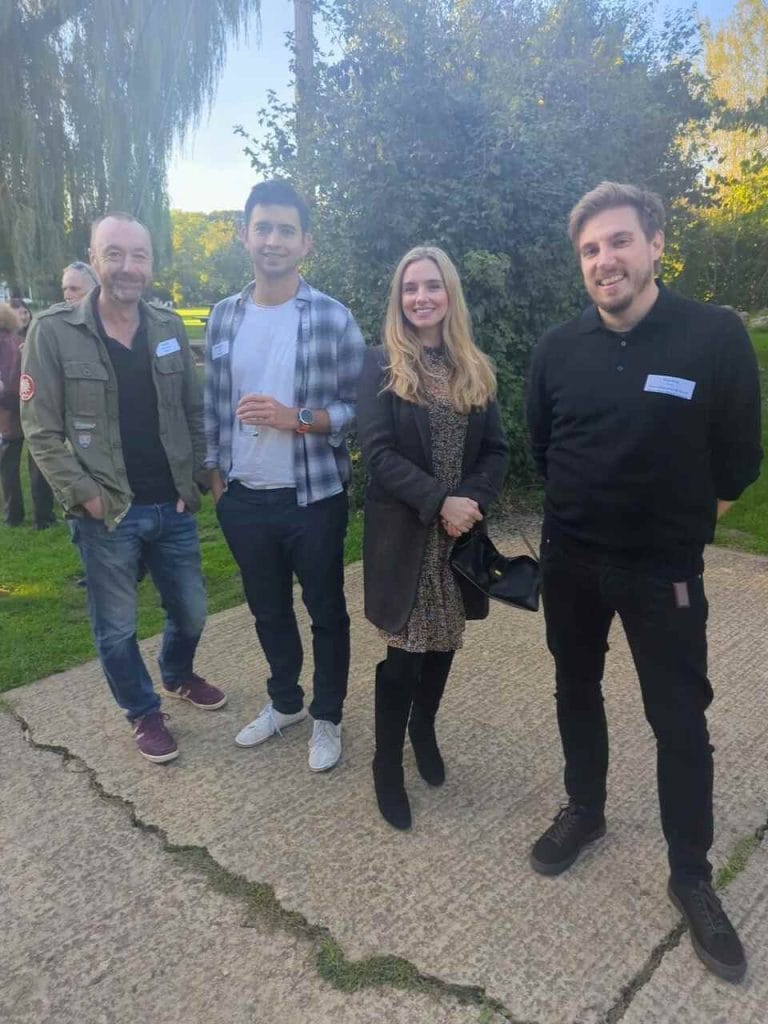 Group photo of four attendees standing outdoors next to a hedge