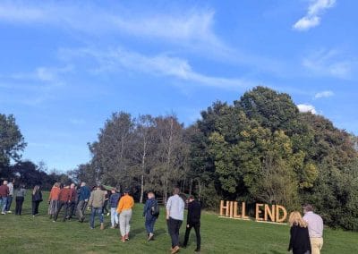 Wide outdoor view of attendees gathered on a grassy field under a blue sky