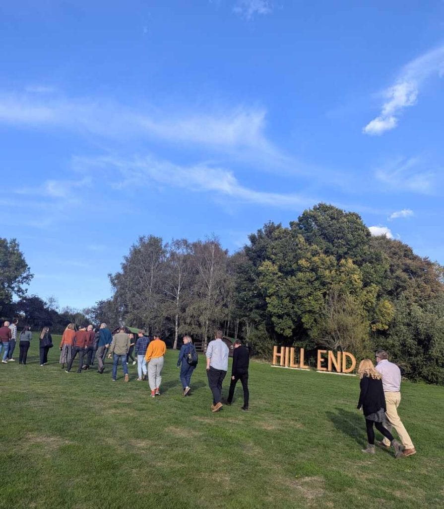Wide outdoor view of attendees gathered on a grassy field under a blue sky