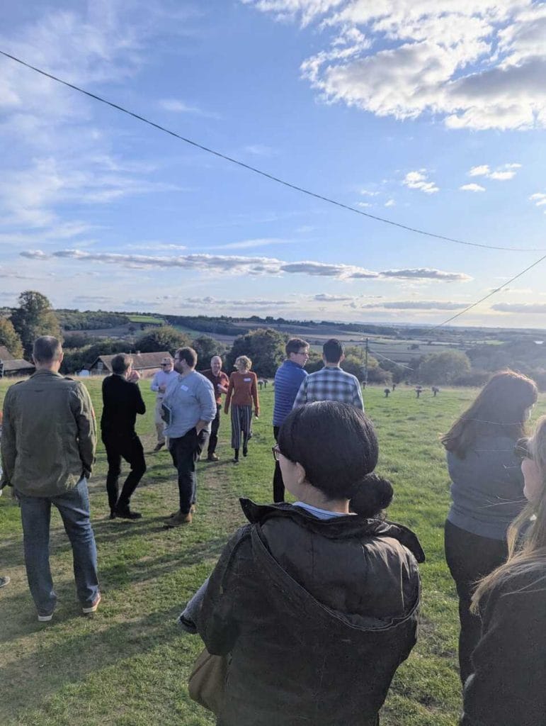 Attendees gathered on a hilltop overlooking countryside under a blue sky