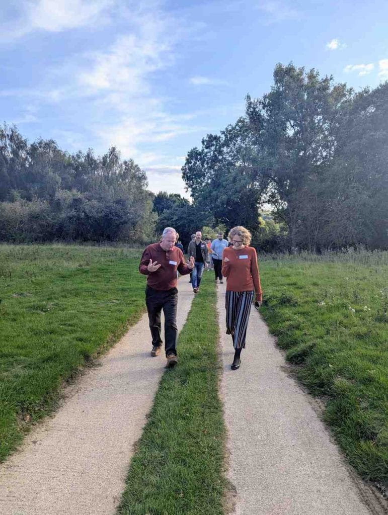 Two people walking down a grass path between trees