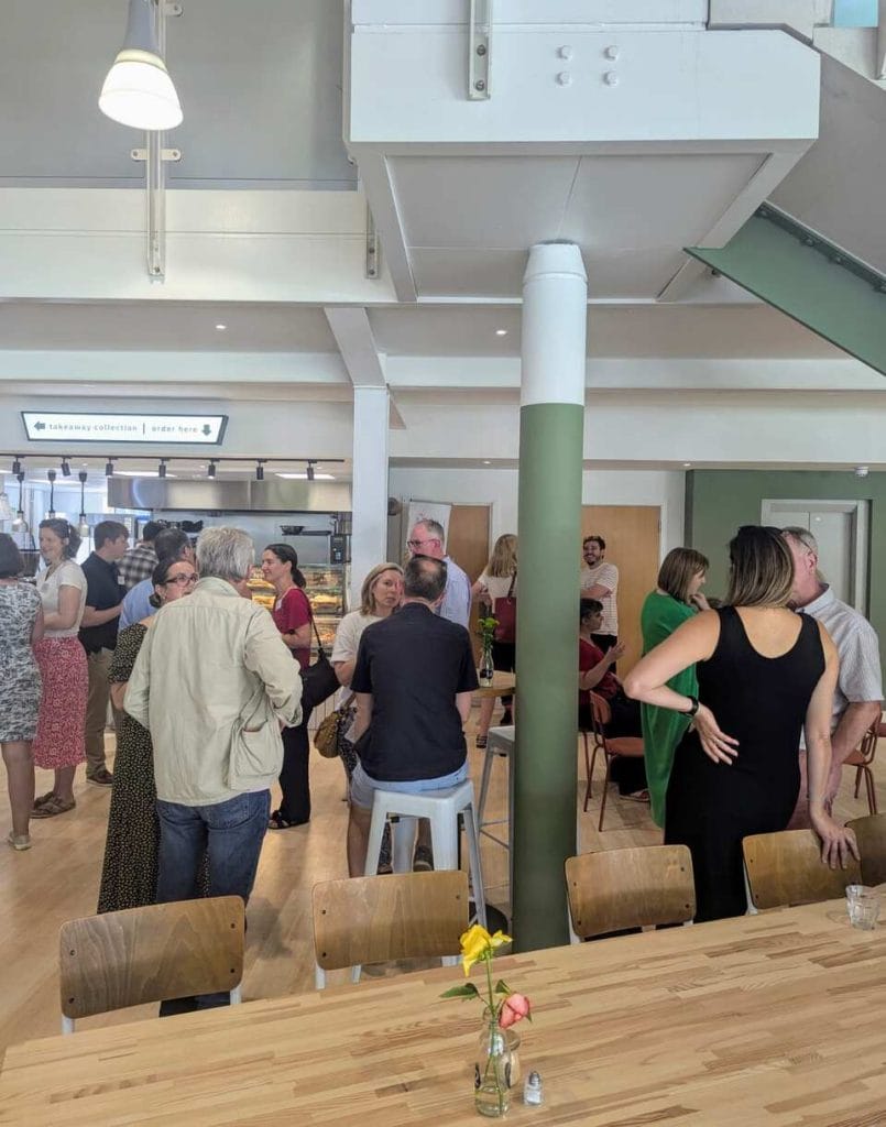 Group of attendees mingling beneath exposed wooden beams