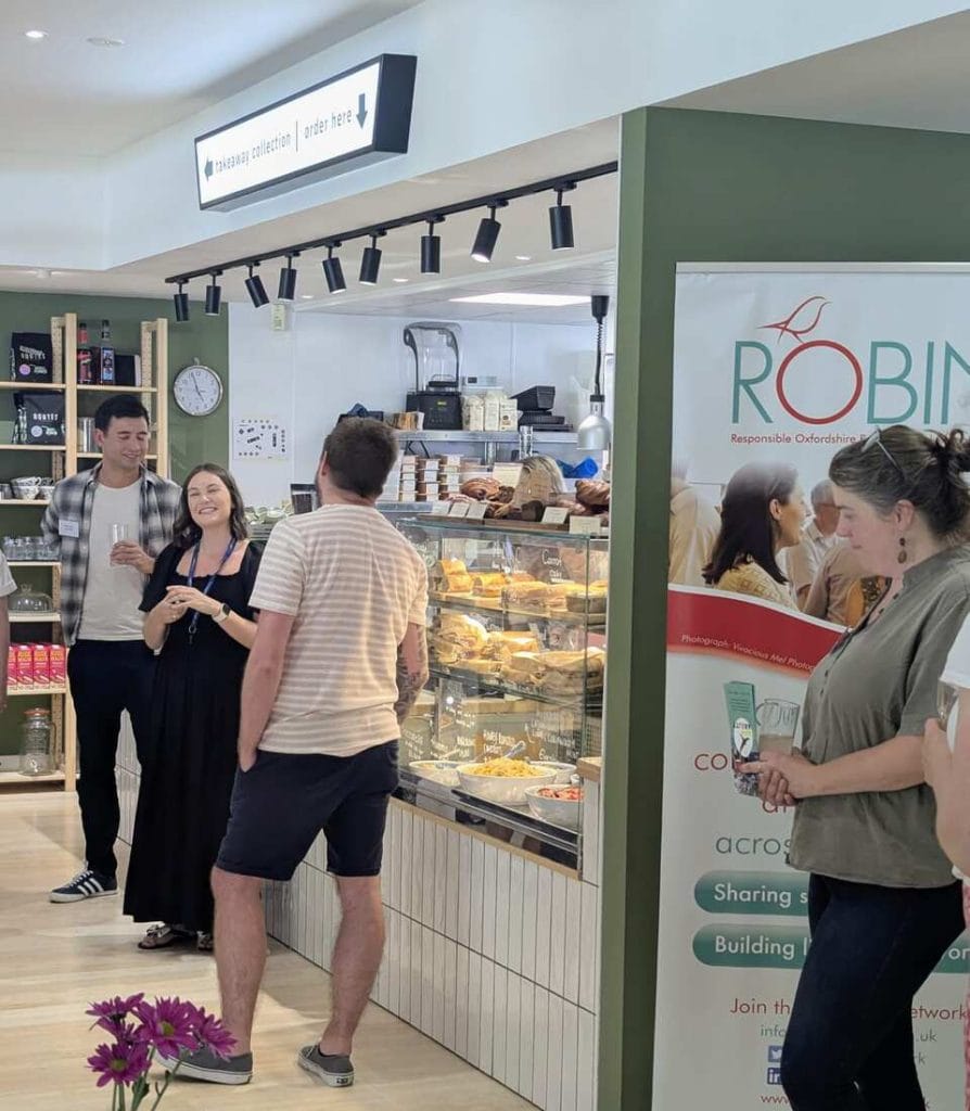 Networking attendees gathered in a cafe area with a green ROBIN sign