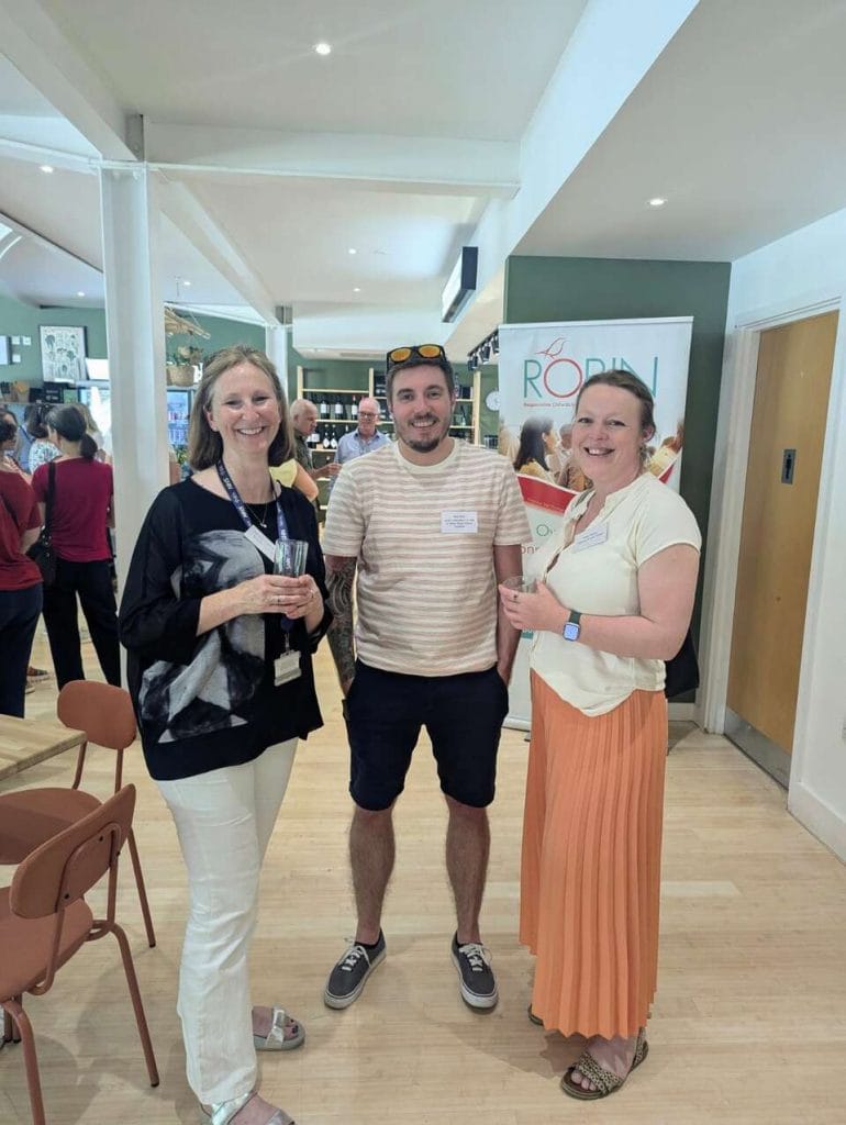 Three attendees posing together in a venue corridor