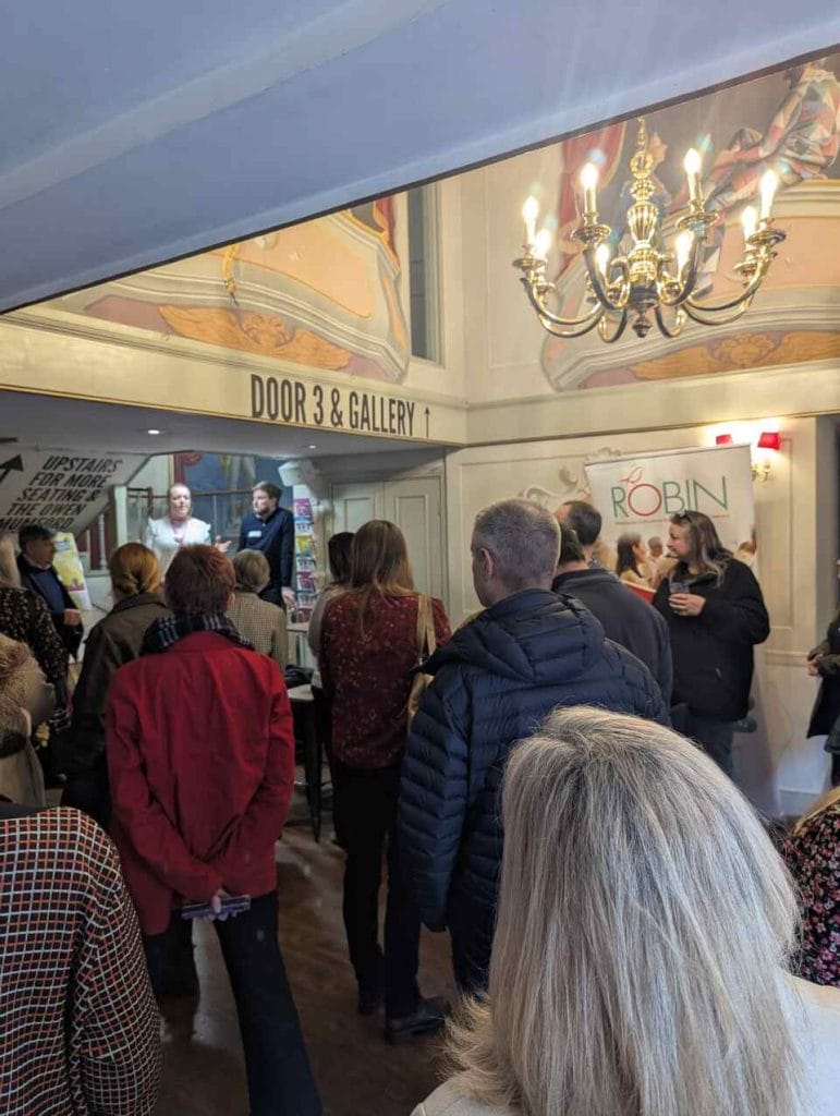 Networking attendees chatting in a chandelier-lit venue lobby