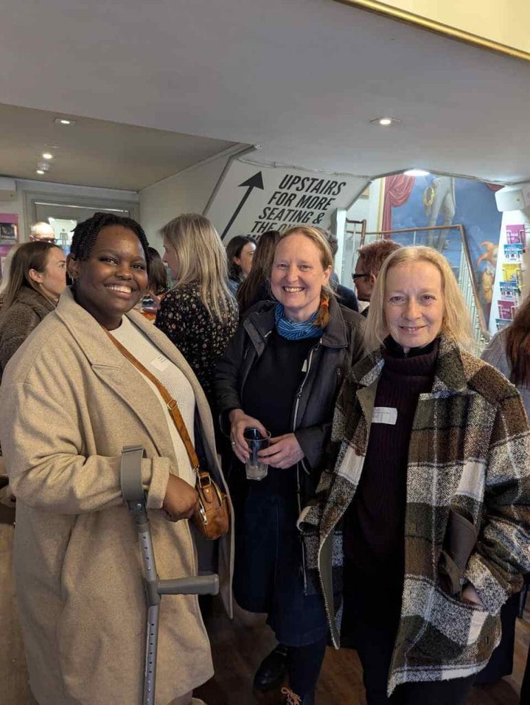 Three women smiling and posing together at a networking event