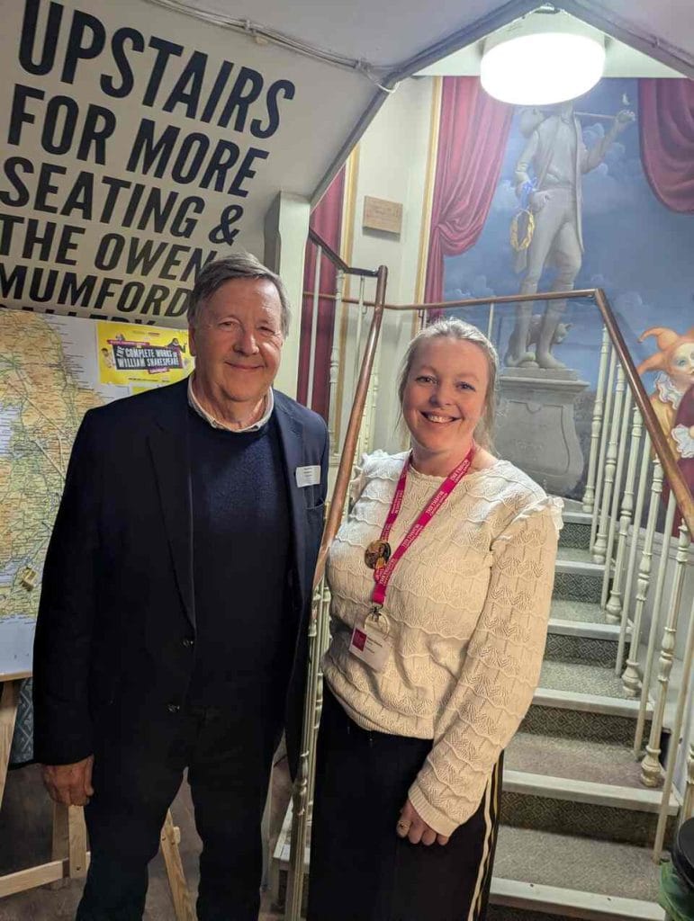 Two men posing together in front of a theatre staircase