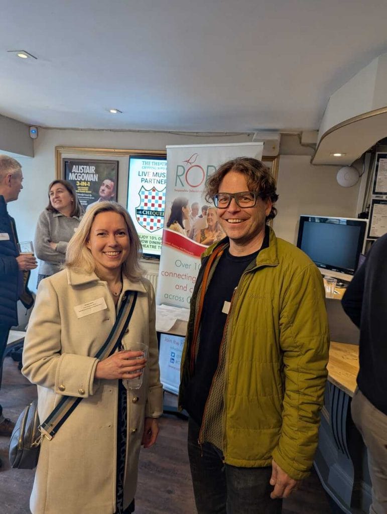 Two attendees holding drinks and chatting at an indoor networking event